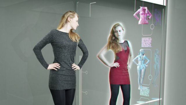 mulher prova roupa em frente ao espelho digital