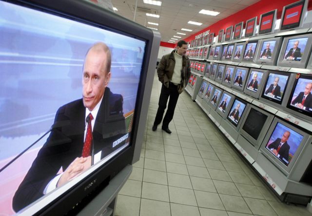 Un hombre observa la transmisión de una rueda de prensa de Putin en los televisores de una tienda de electrónicos en Moscú, 31 de enero de 2006.