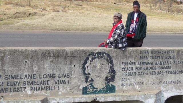 La mère d'Eudy Simelane, Mally (à gauche), et le père Khotso (à droite) sont assis sur le pont construit en l'honneur de leur fille assassinée, à côté d'une fresque représentant son visage sur le mur