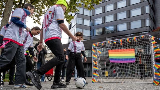 LGBTQ+ rights activists kick a football into a goal covered in rainbow flags as part of a protest against the 2022 Qatar World Cup outside Fifa's museum in Zurich