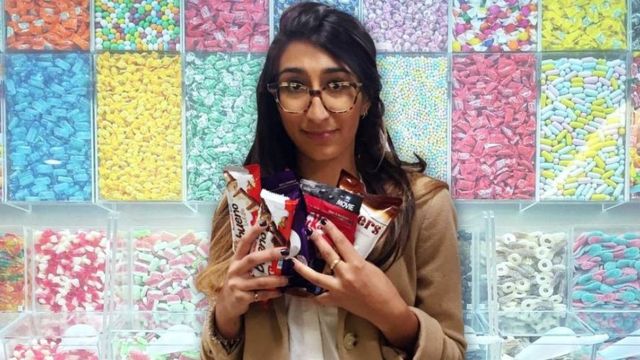 Una mujer con muchos chocolates y dulces en la mano