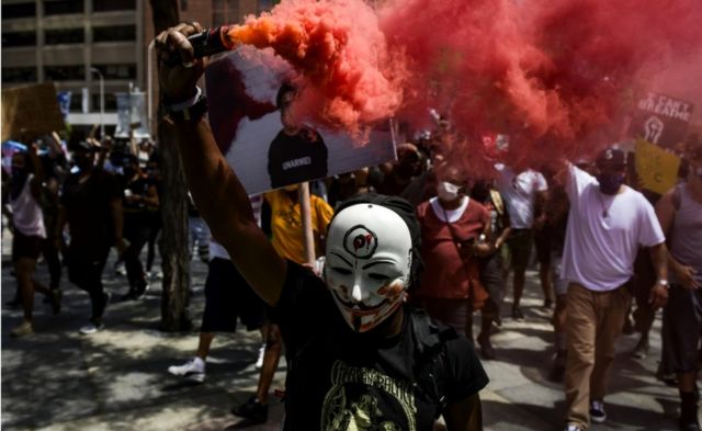 A man holds a smoke grenade as thousands of people march in Denver, Colorado, 30 May 2020