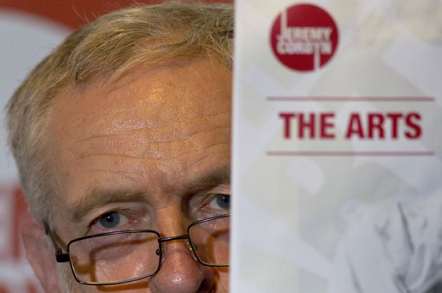 Jeremy Corbyn peers around a leaflet entitled The Arts