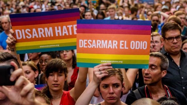 Dos personas con carteles que dicen "desarmar el odio" en una manifestación por los derechos LGBT.