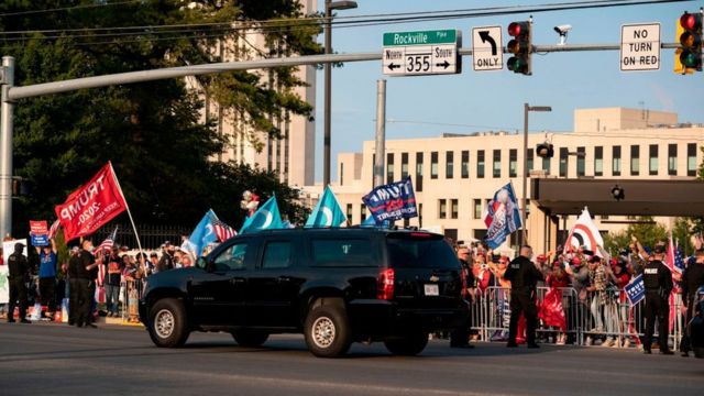 Un auto del convoy presidencial pasa frente a simpatizantes del presidente frente al hospital Walter Reed.