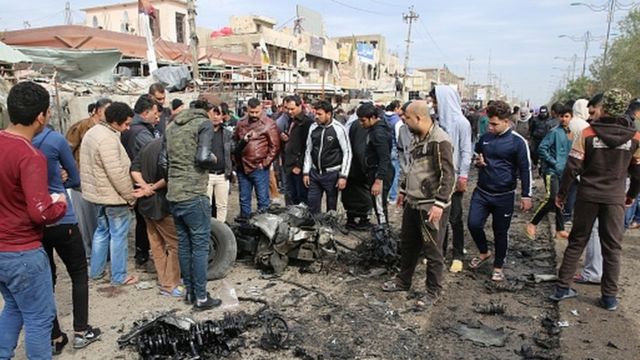 Des gens rassemblés autour des restes du véhicule détruit à la suite d'une explosion à Sadr City (le 2 janvier 2017)