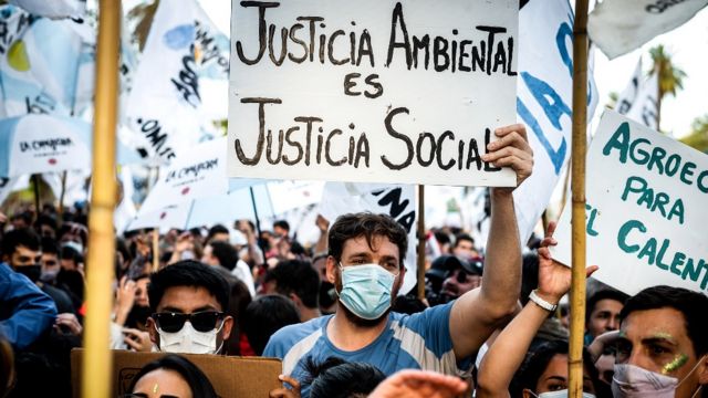 Jovens com uma placa que diz "justiça ambiental é justiça social"