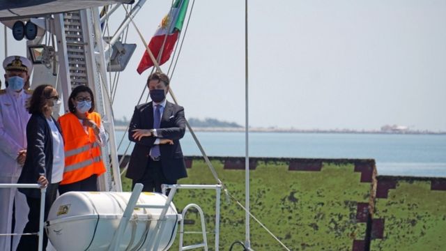 El primer ministro italiano Giuseppe Conte se encuentra en la cubierta de un barco de la Guardia Costera italiana.