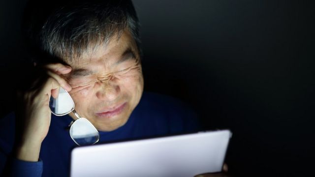Homem fechando olhos em frente ao laptop