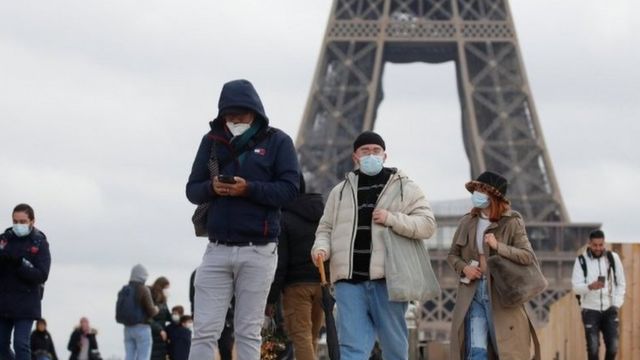 People, wearing protective masks, walk through the Trocadero square, near the Eiffel Tower in Paris.