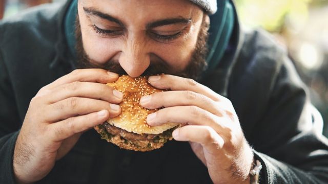 Hombre comiendo una hamburguesa