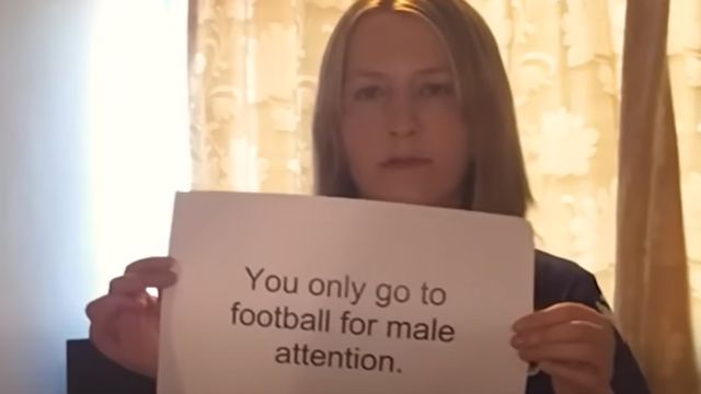 Woman holding poster saying 'you only go to football for male attention',