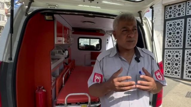 Mahmoud gesticula enquanto fala em frente a ambulância