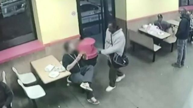 Um homem aponta uma faca para uma pessoa em um restaurante
