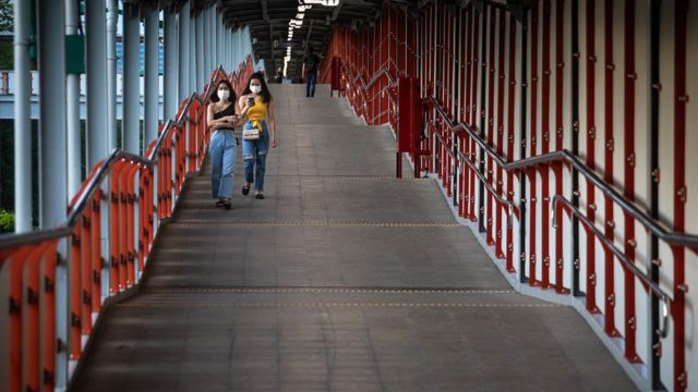 ผู้หญิง 2 คนกำลังเดินบนทางเชื่อมสกายวอล์กสู่สถานีรถไฟฟ้าบีทีเอส