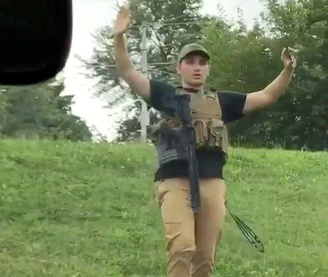 Dmitriy Andreychenko walks downhill with a gun sling and hands in the air before he is apprehended by police near a Walmart in Springfield, Missouri