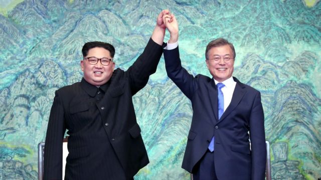Kim Jong-un and Moon Jae-in raise their hands triumphantly at a Korean summit