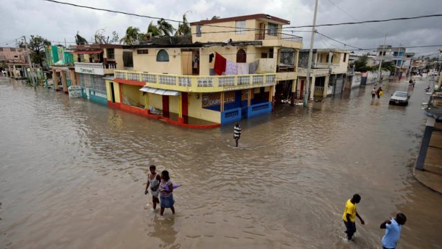 People walk in a flooded area after Hurricane Matthew in Les Cayes