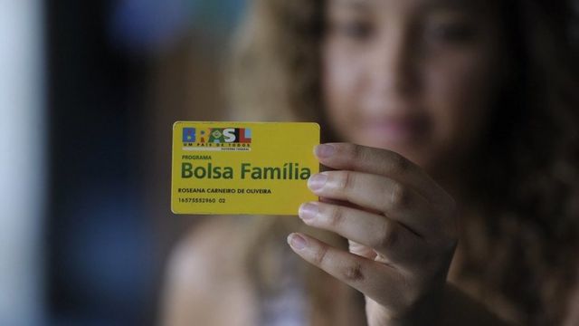 Mulher segura cartão do Bolsa-Família