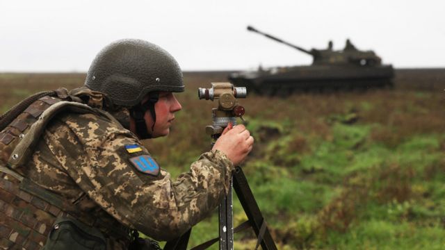 A Ukrainian soldier measures and takes aim for a self-propelled gun.