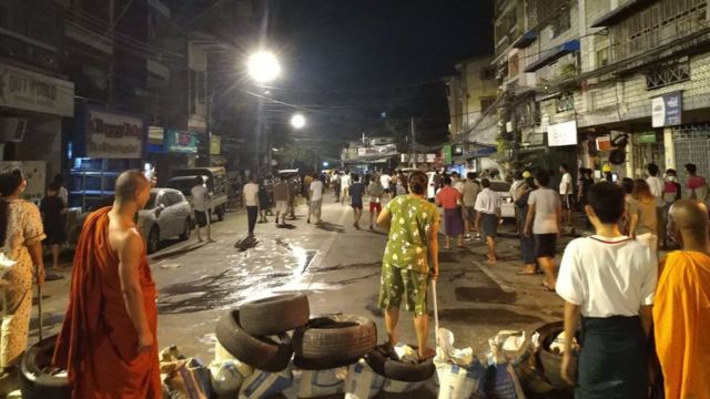 Protesters stand in front of a barricade at night in Myanmar