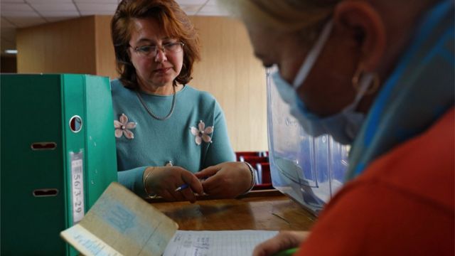 An election official checks a woman's passport in Mariupol to verify her identity