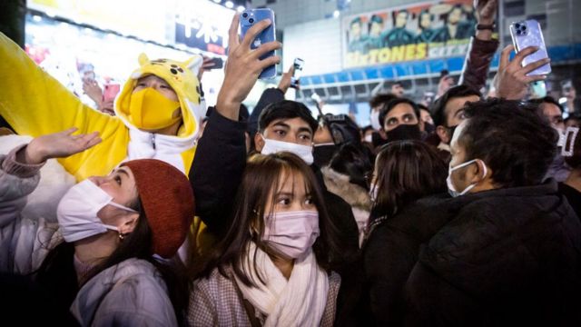 Personas conglomeradas en las calles de Japón durante la celebración de Año Nuevo. Un hombre lleva un traje de Pikachu
