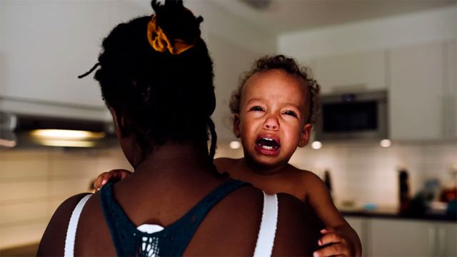 Una madre sostiene a un niño que llora