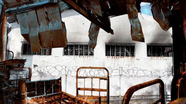 Un bâtiment de prison blanc d'Olenivka encadré par l'intérieur détruit de l'entrepôt touché par des explosions.
