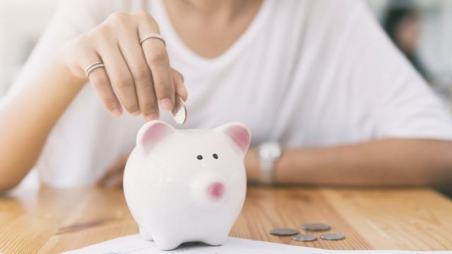 Woman putting money in a piggy bank