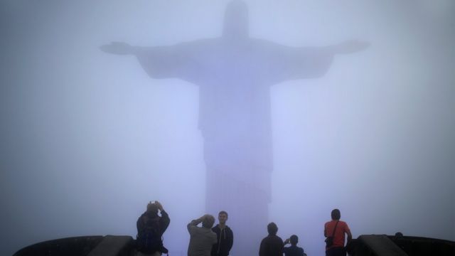 Turistas fotografam Cristo Redentor sob névoa