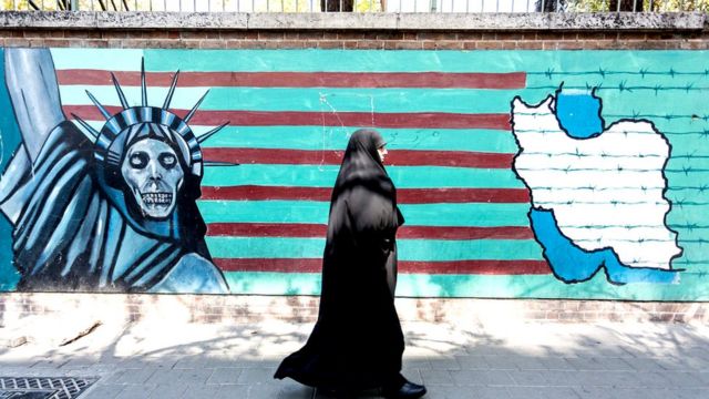 Mujer pasando por mural antiamericano en Teherán