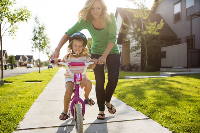Una niña en bicicleta con su madre al lado