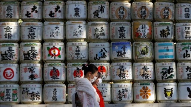Kimono-clad women wearing protective face masks walk in front of Japanese Sake barrel decorations for the year-end and New-Year at Meiji Shrine, amid the coronavirus disease (COVID-19) outbreak, in Tokyo, Japan, December 31, 2020.