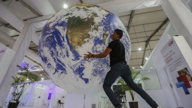 A man holds a globe at a pavilion at COP27