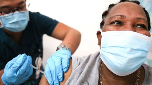 A black woman receives the vaccine.