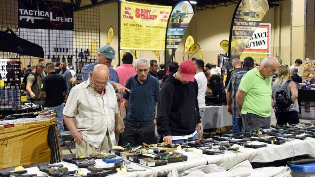 Homens observam armas expostas na Flórida Gun Show