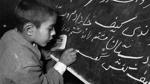 Niño iraní escribiendo en una pizarra