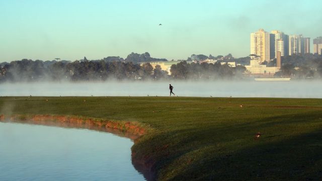 Una persona corriendo en la hierba, con vapor de agua sobre un charco en un escenario frío