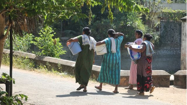 Mulheres indianas caminham até um rio para lavar roupa