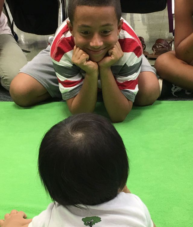 Un niño le sonríe a un bebé durante un programa de Roots of Empathy.
