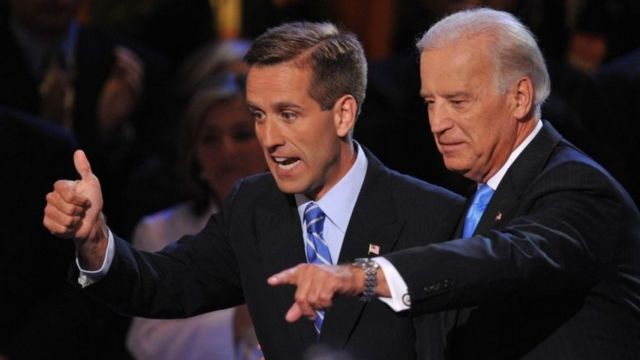 Joe Biden and Beau Biden wave from a stage.