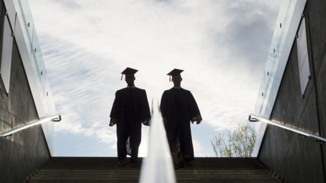 设计图片：两位大学毕业生在楼梯上往上走的倒影