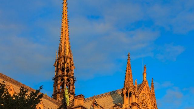 Imagem da torre agulha em Notre Dame, antes do incêndio, sob a luz amarelada do pôr do sol