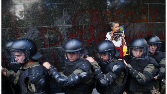 Женщина стоит недалеко от полицейского кордона во время беспорядков возле здания Генеральной прокуратуры 17 сентября 2018 года