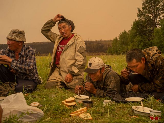 Local firefighter volunteers take a lunch break in a field in Magaras, central Sakha, Siberia, Russia, July 1, 2021.
