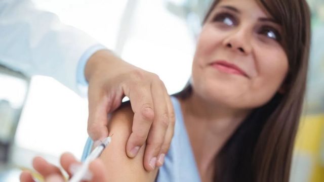 Mujer recibiendo una vacuna en el brazo.