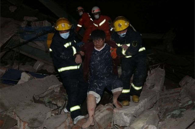 Спасатели выводят пострадавшего из-под обломков рухнувшей гостиницы