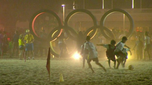 Children playing football in front of Olympic rings