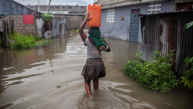 Una mujer intenta trasladarse por un terreno inundado.